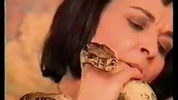 Dark-haired woman thrusts a serpent into her vagina while on hands and knees